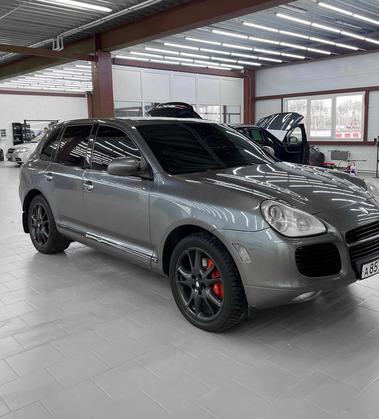 Серый Porsche Cayenne с тёмными стёклами в боксе