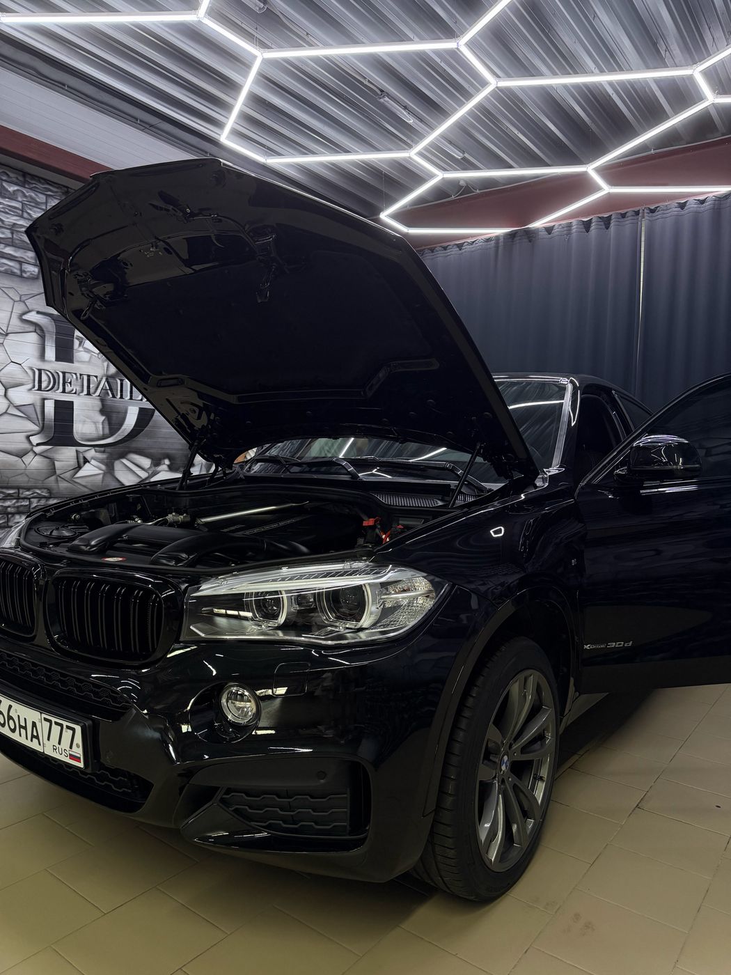 Чёрный BMW с открытым капотом под шестигранными лампами